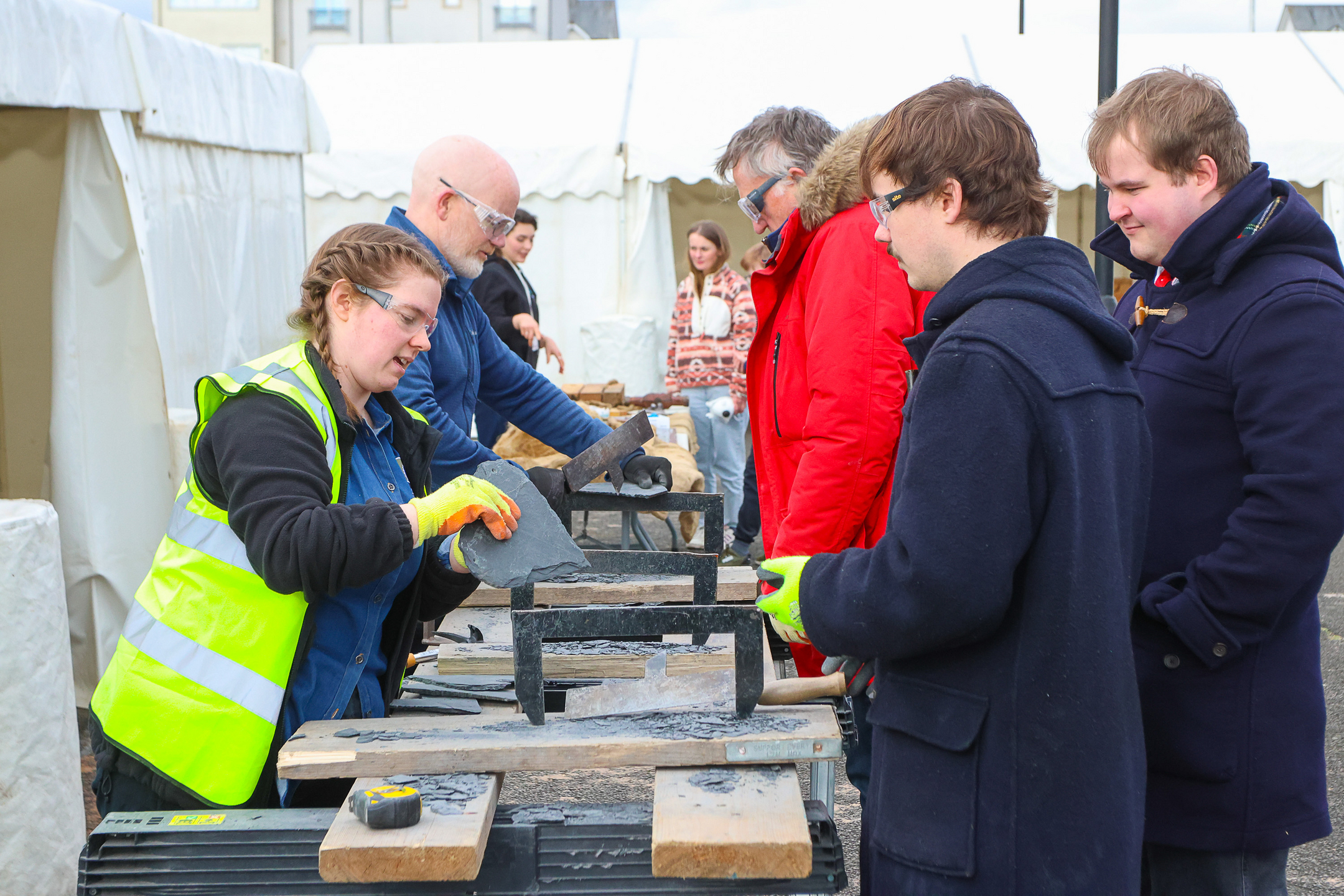 Woman shows piece of slate roofing to visitors