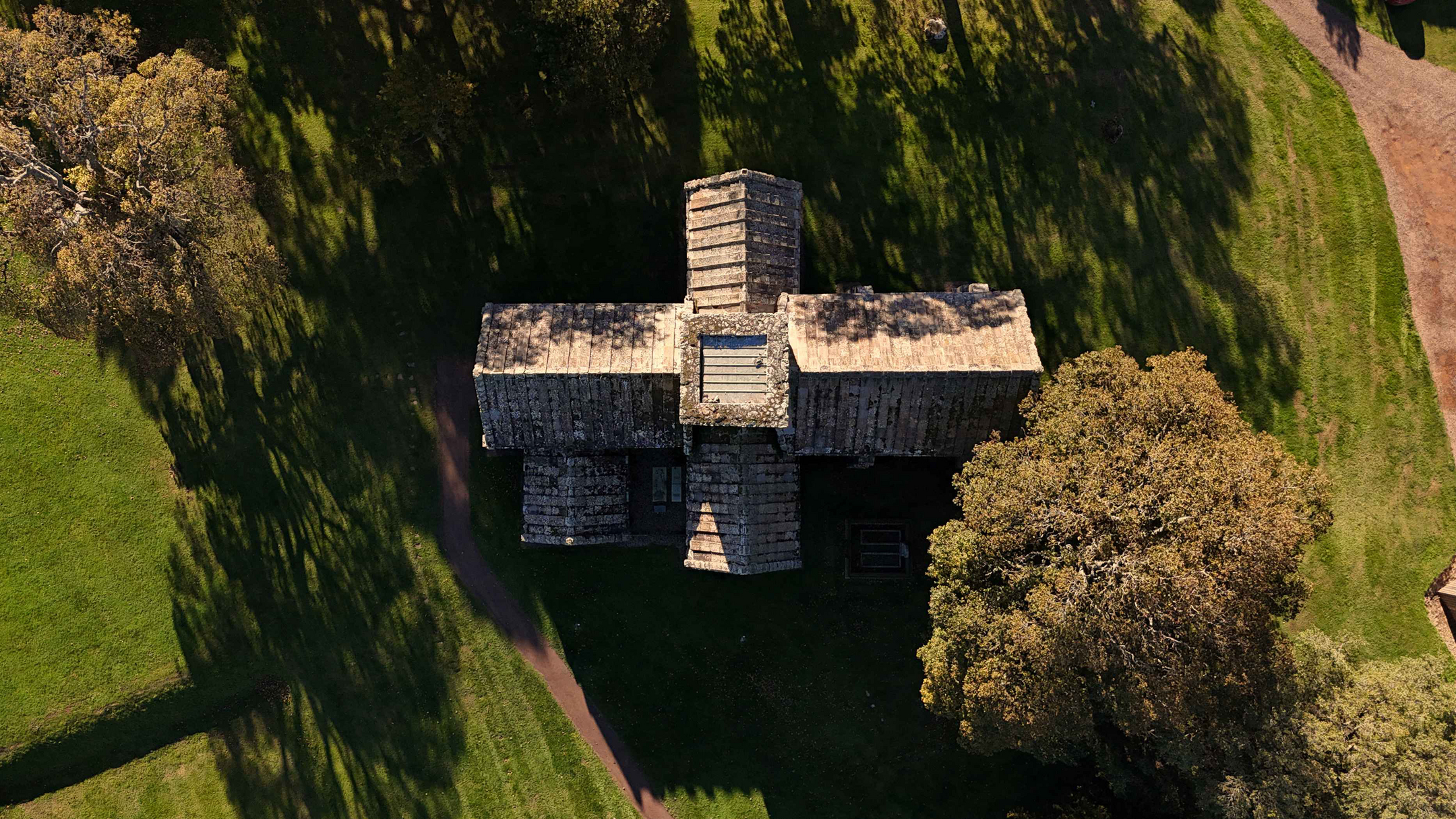 Church building from directly above, making cross shape in an otherwise green landscape