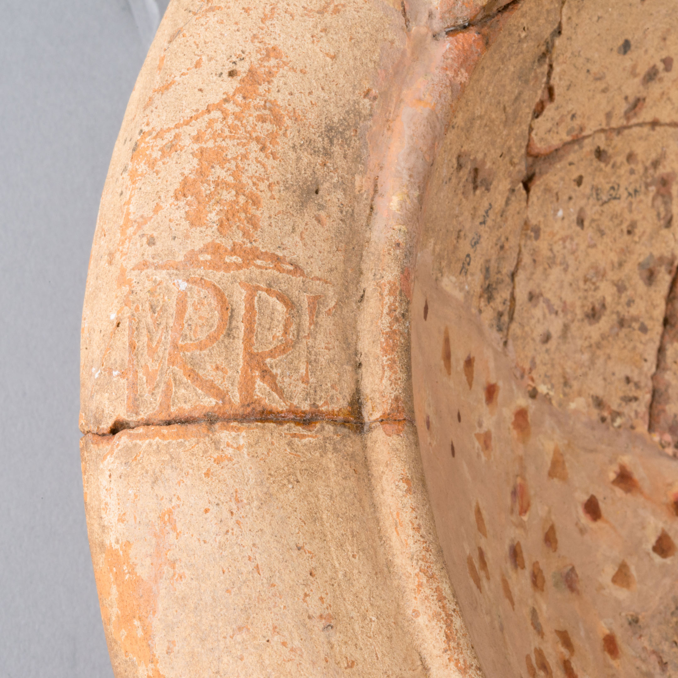 Close-up of Roman terracotta bowl rim with carved letters from Bearsden Bath House.