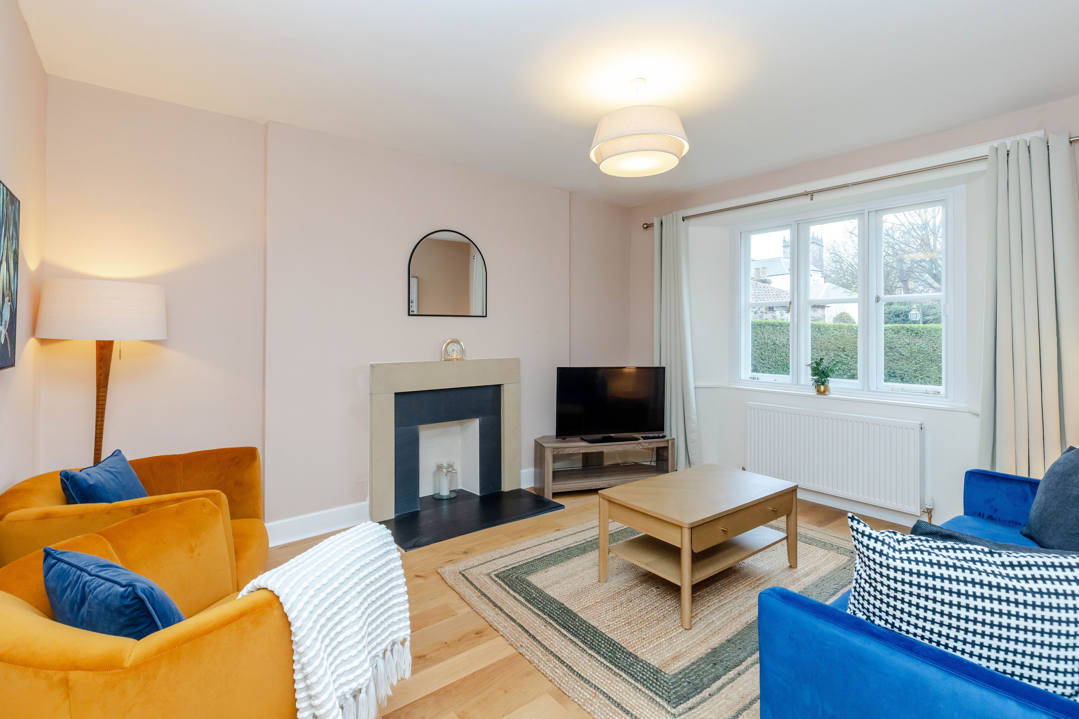 A neutral coloured living room with colourful yellow chairs and a colourful blue sofa, with a nice fireplace and coffee table in the centre of the room